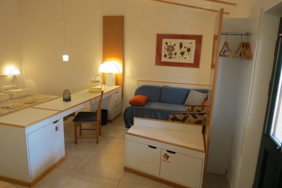 Blick ins Zimmer FeWo am Zwenkauer See Kleine Wohnung mit blauer Couch, Tisch, Stuhl und gemütlicher Beleuchtung.