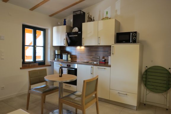 Küchenzeile FeWo am Zwenkauer See Kleine moderne Küche mit Tisch und Stühlen, Küchenschränken und Geräten.