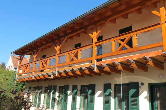 FeWo am Zwenkauer See mit Balkon Hölzernes Obergeschoss eines Gebäudes mit Balkon und grünen Fenstern.