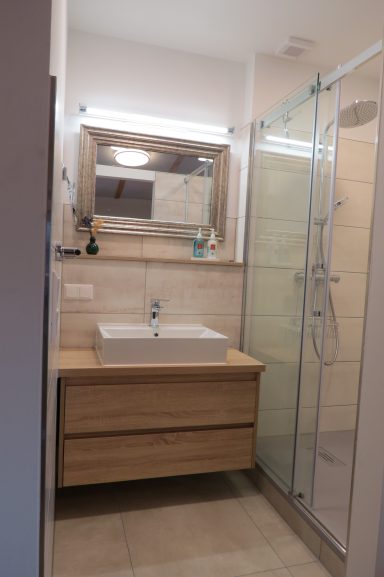 Moderner Waschtisch FeWo am Zwenkauer See Helles Badezimmer mit Doppelwaschbecken, Spiegel und gläserner Dusche.