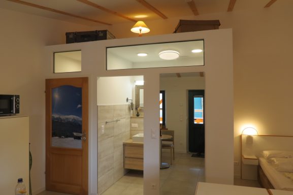 FeWo am Zwenkauer See mit morderner Badsausstattung Heller Raum mit Küche, Bad und Zugang zu einem Schlafbereich. Moderne Innenausstattung.