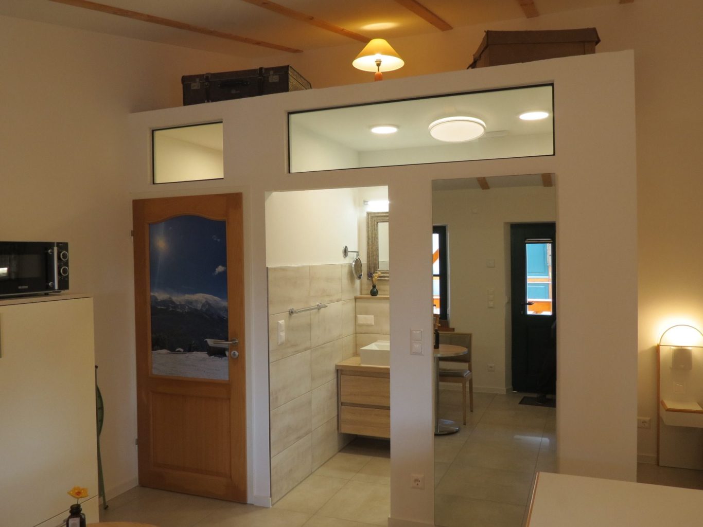 Bild vergrößern... Heller Raum mit Küche, Bad und Zugang zu einem Schlafbereich. Moderne Innenausstattung.